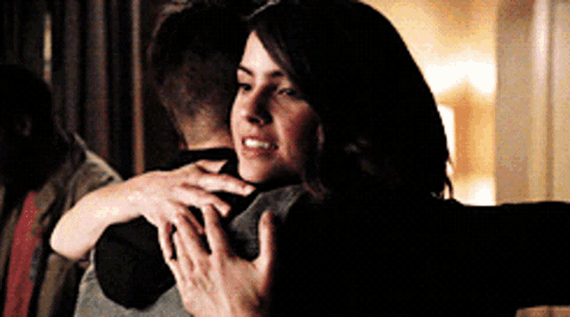 a woman is hugging a man in a dark room and smiling