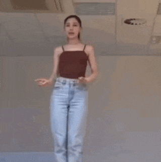 a woman is dancing in a room with a ceiling fan .
