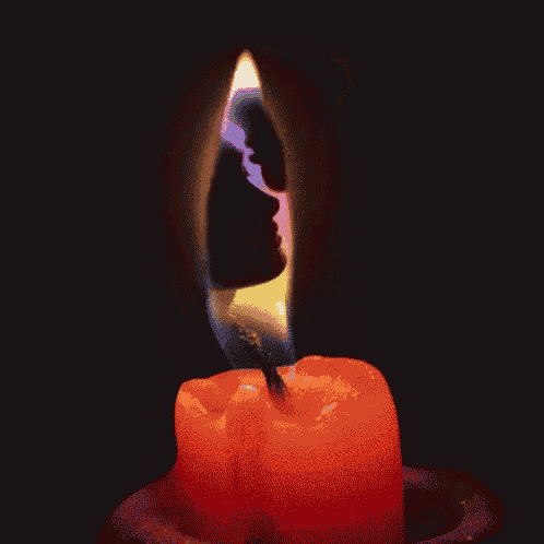 a close up of a candle with a rainbow flame coming out of it