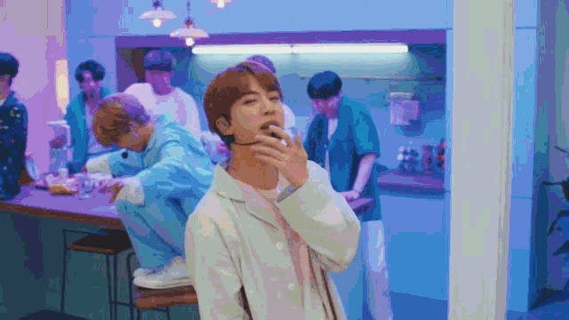 a man is smoking a cigarette in front of a group of men in a kitchen .