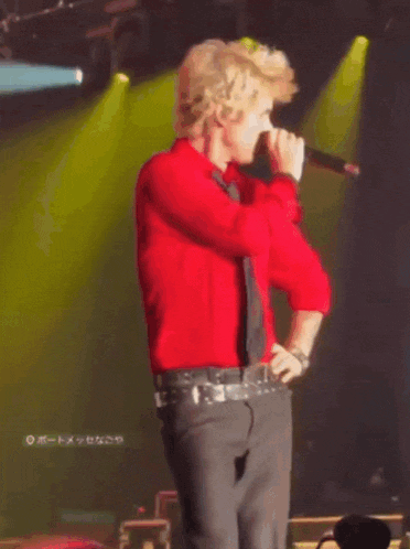a man in a red shirt and tie is standing on stage