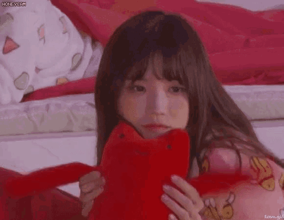 a young girl is holding a red stuffed animal in her hands .