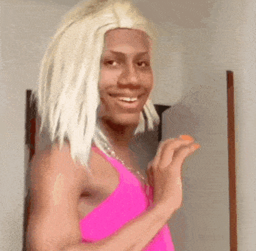a man with blonde hair and a pink tank top is smiling .