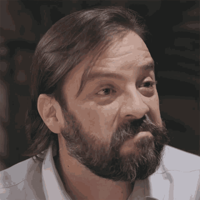 a man with long hair and a beard is looking at the camera