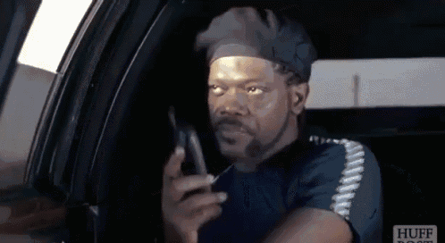 a man in a hat is talking on a cell phone while sitting in the back seat of a car ..