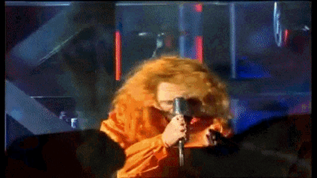 a woman with red hair is singing into a microphone in front of a crowd