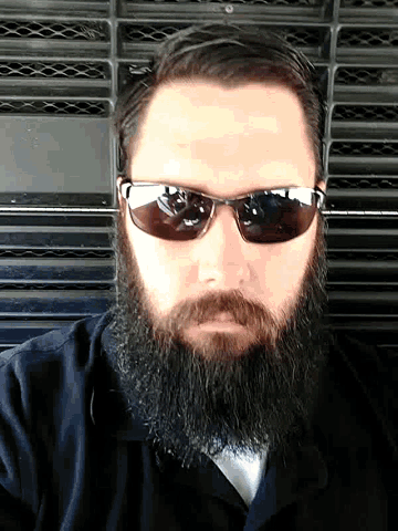 a man with a beard wearing sunglasses and a black jacket