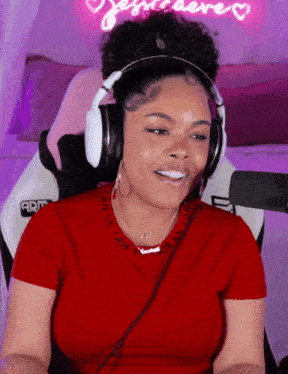 a woman wearing headphones and a red guess shirt smiles