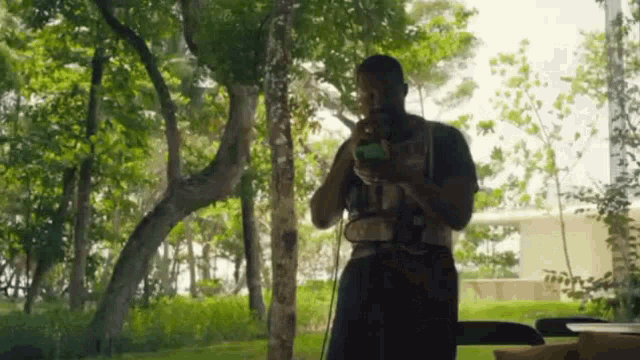 a man is standing in front of a window in a park looking at his cell phone .