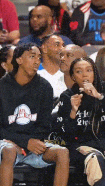 a man wearing a black hoodie that says ' atlanta dream team ' on it sits next to a woman