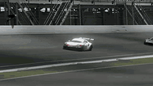 a race car is driving down a track with other cars behind it