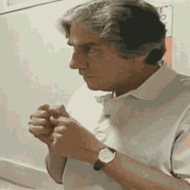 a man wearing a watch is praying with his hands folded in prayer