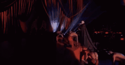 a group of people are dancing on a stage in a dark room with a lot of lights .