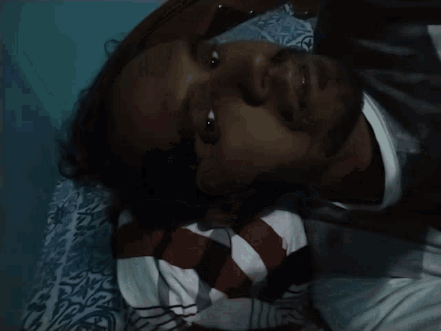 a man with a beard is laying on a bed with a striped shirt on