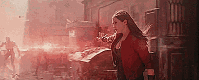 scarlet witch is standing in front of a building in a city .