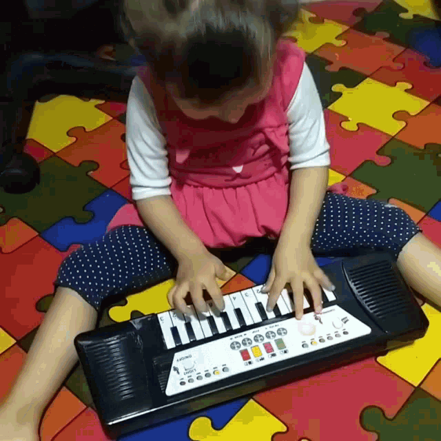 a little girl is playing a keyboard that says casio on the front