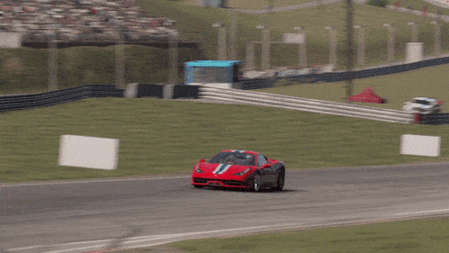 a red sports car is driving on a track with a green curb