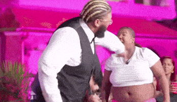 a man in a suit is dancing with a woman in a white crop top .