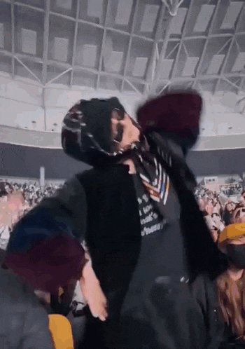 a man wearing a hoodie and a scarf is dancing in a crowd