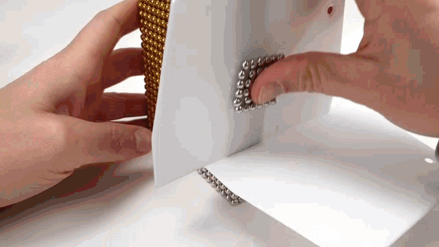 a person 's hand is holding a stack of magnetic balls