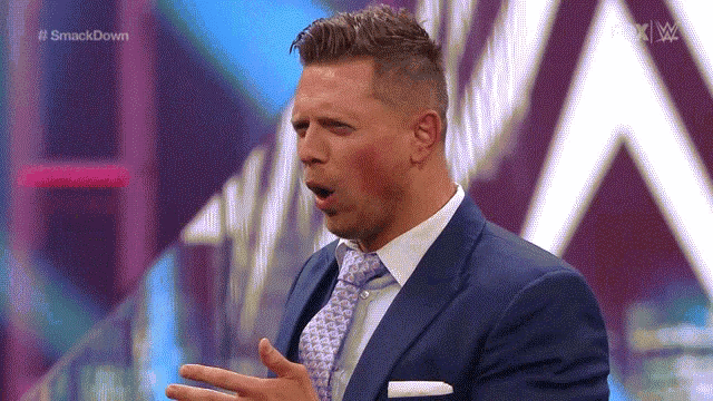 a man in a suit and tie is standing on a stage with his mouth open ..