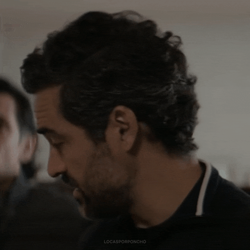a close up of a man 's face with a beard and curly hair .