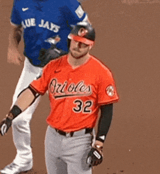 a baseball player wearing an orioles 32 jersey stands on the field