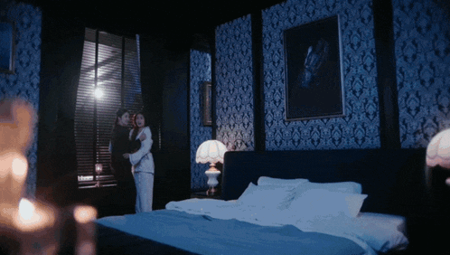 a couple standing next to each other in a dark bedroom