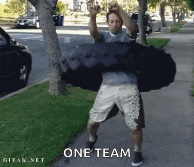 a man is standing on a sidewalk holding a large bag on his shoulders .