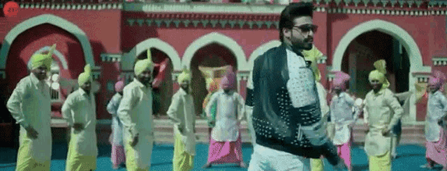 a man in a leather jacket is dancing in front of a group of people .
