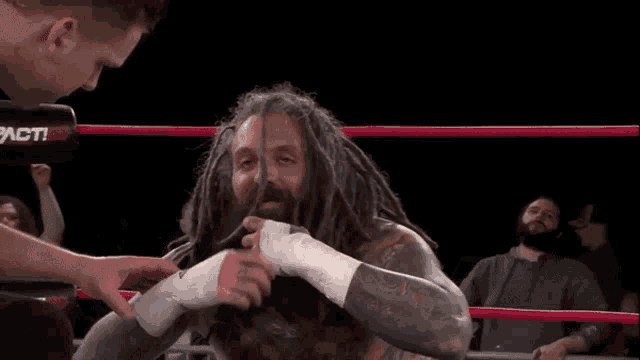 a man with dreadlocks is in a boxing ring with the word impact on the side