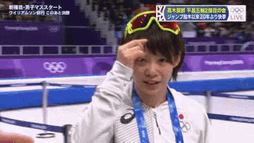 a person wearing sunglasses and a medal around their neck stands in front of a sign that says live