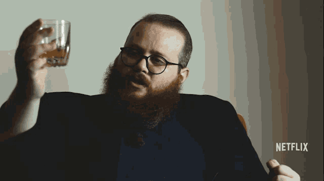 a man with a beard is holding a glass of whiskey in front of a netflix sign
