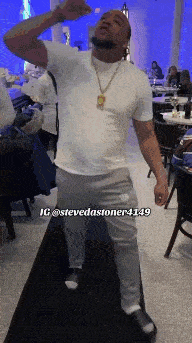 a man in a white shirt and grey pants is dancing in a restaurant