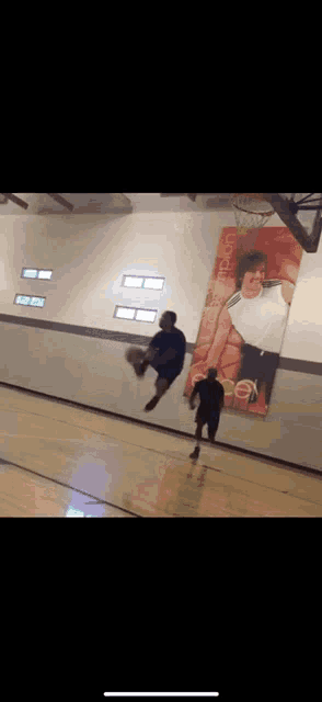 a man is jumping in the air while playing basketball in front of a poster of a man holding a basketball