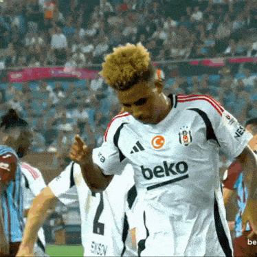 a soccer player wearing a beko jersey stands on a field