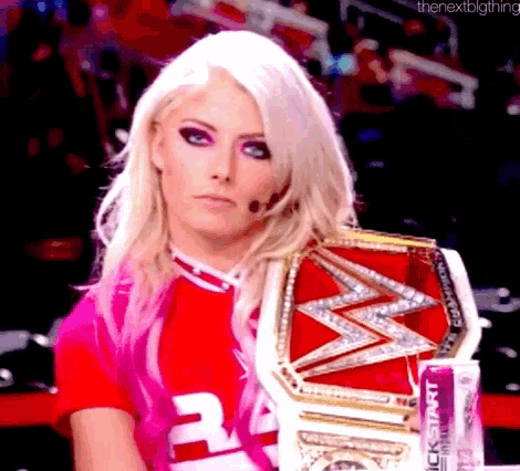 a woman in a pink shirt is holding a pink wrestling belt .