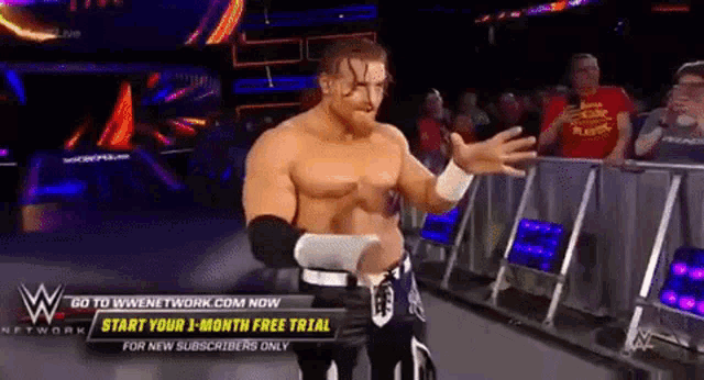 a man in a wrestling ring with a sign that says go to wwennetwork.com now