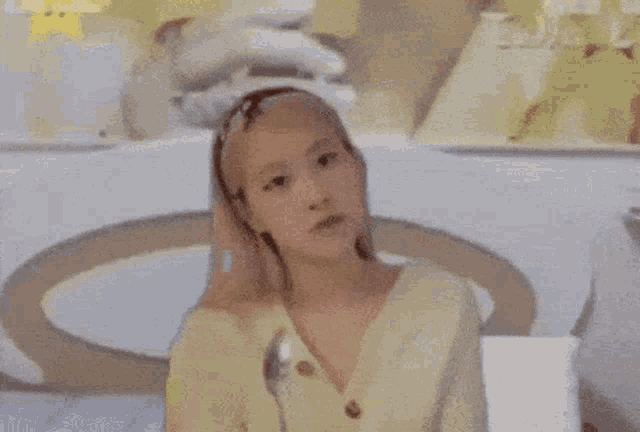 a woman wearing a yellow cardigan and a headband is talking on a phone .