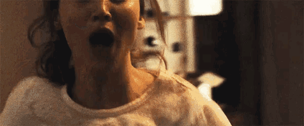 a woman is screaming with her mouth open in a dark room .