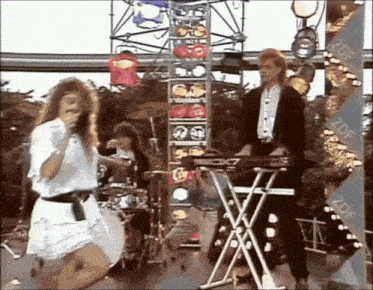a woman in a white dress is singing into a microphone