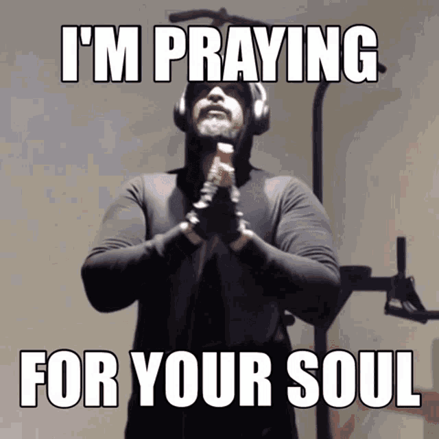 a man wearing headphones and a hoodie says " i 'm praying for your soul "