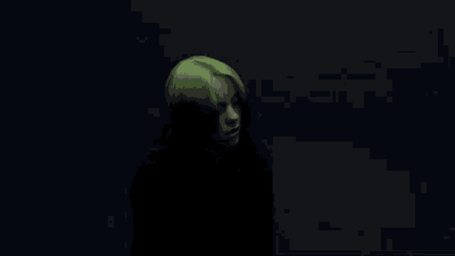billie eilish has green hair and is wearing a black shirt