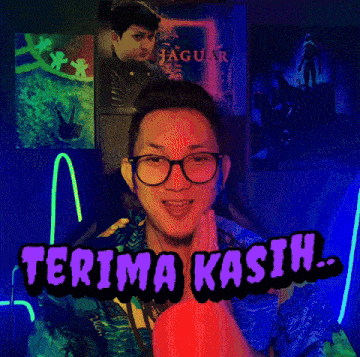 a man wearing glasses says terima kasih in front of a jaguar poster