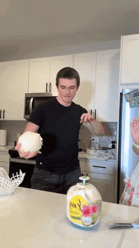 a man in a black shirt is holding a coconut in front of a bottle of bamboo soap