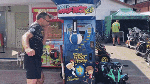 a man stands in front of a machine that says get your first trophy on it