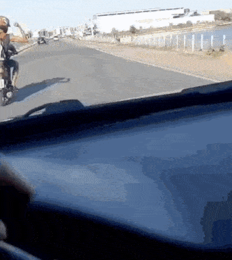 a man is riding a motorcycle down a highway with a fence in the background