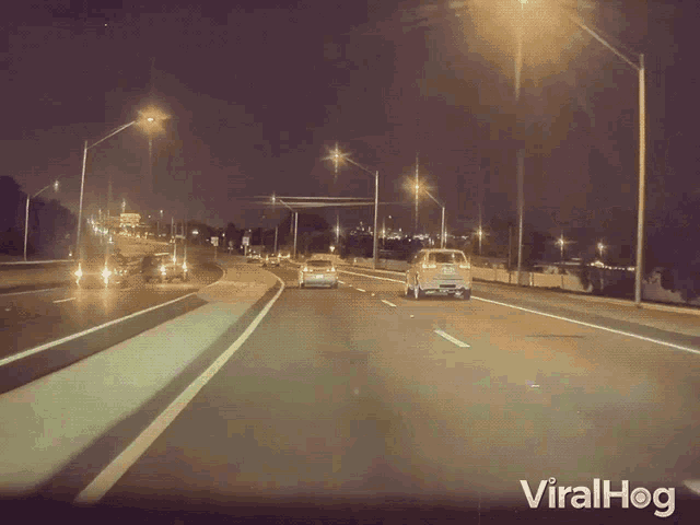 a car is driving down a highway at night with viralhog written on the bottom of the screen