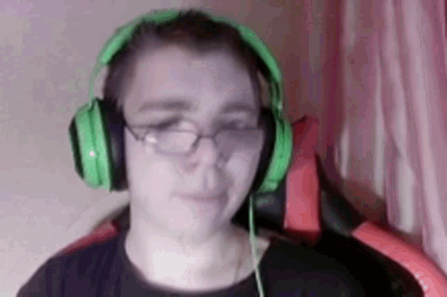 a person wearing green headphones and glasses is looking at the camera