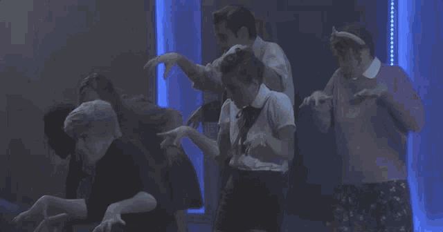 a group of people are dancing in a room with blue lights .